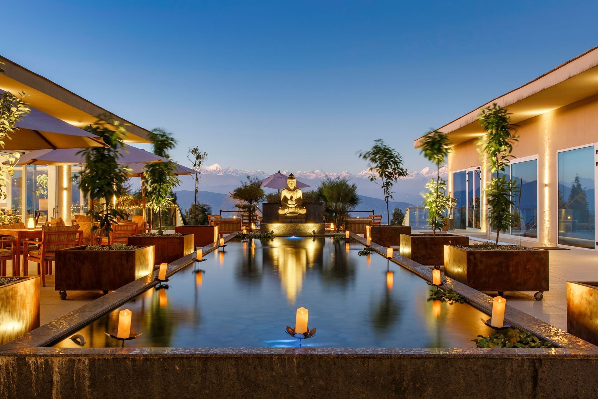 Outdoor terrace with a reflective pool, Buddha statue, and mountain view at The Terraces Resort & Spa