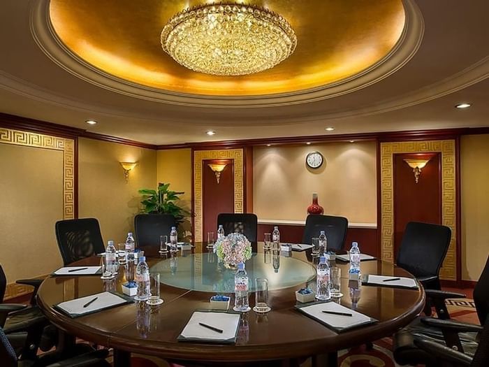 Set up round wooden table with water bottles under a chandelier in VIP room 2 at Celebrity International Grand Hotel 