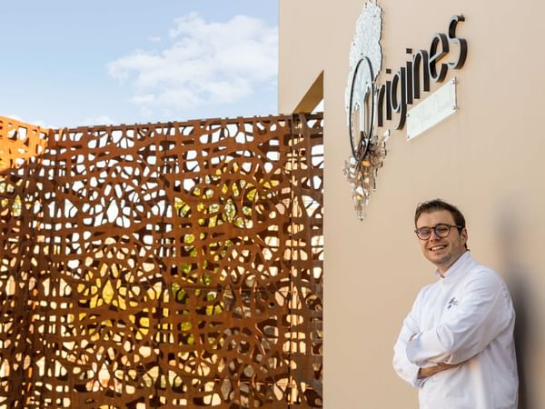 Chef posing on a wall with the logo at Hôtel de l'Europe