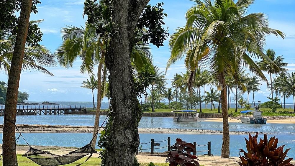 Beach view with hammock under trees at The Naviti Resort in Korolevu.
