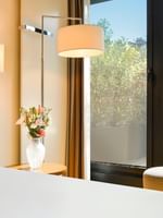 Deluxe Terrace Room with White bed by a floral vase under a large floor lamp at Warwick Geneva
