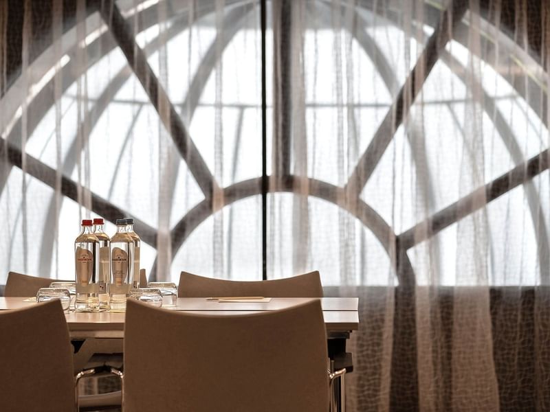 La salle de réception Barsey II, équipée d'une table et de chaises, située devant une grande baie vitrée à l'hôtel Barsey by Warwick à Bruxelles.