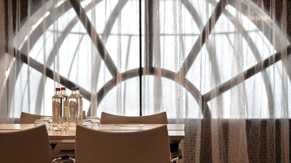 La salle de réception Barsey II, équipée d'une table et de chaises, située devant une grande baie vitrée à l'hôtel Barsey by Warwick à Bruxelles.