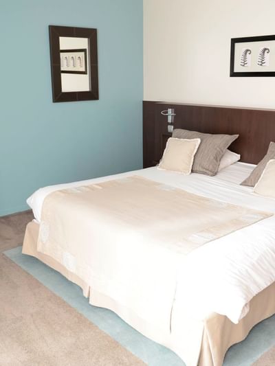 Chambre d'hôtel avec lit, télévision, bureau, et deux cadres muraux décoratifs.