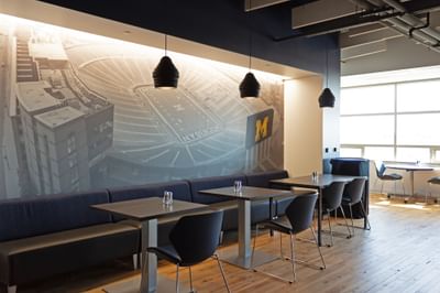 Michigan Ross Conference Center working area with a Michigan Wolverines stadium mural, tables, and chairs.