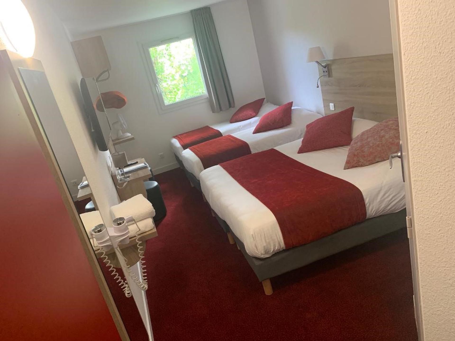A room with twin beds and a double bed at hotel Costieres