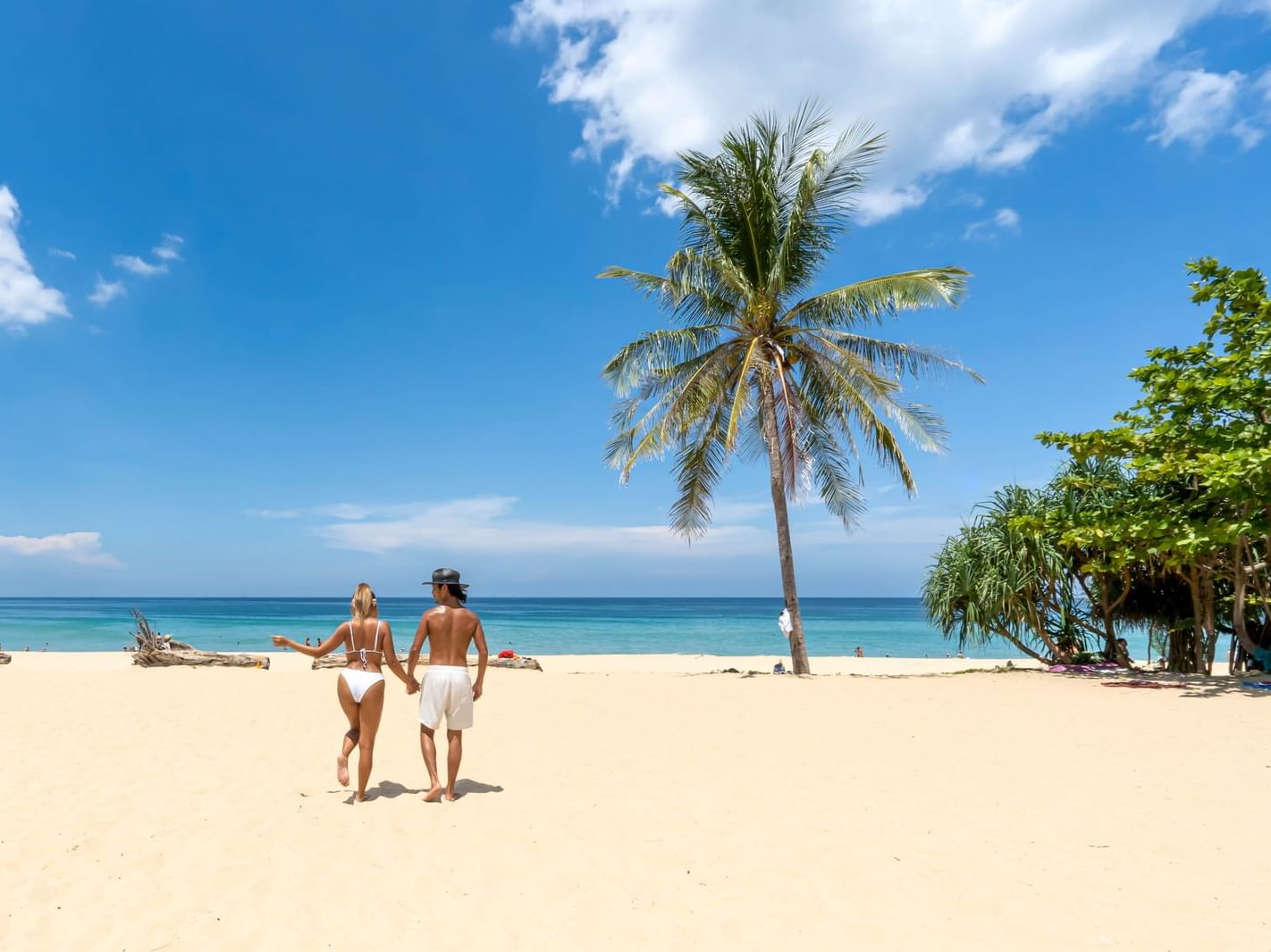 A couple is walking and chilling on the white sandy Karon Beach with turquoise blue sea as a backdrop
