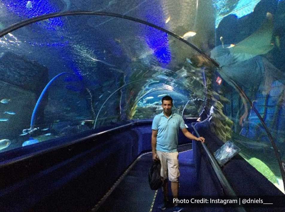 Man posing in Aquaria KLCC underwater tunnel, a popular local attraction near Imperial Lexis Kuala Lumpur