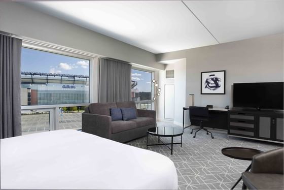 room with bed, sofa, desk and view to gillette stadium