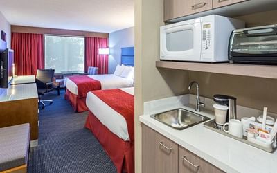Cozy bed and TV arranged with mini kitchen area at Fort McMurray Hotels