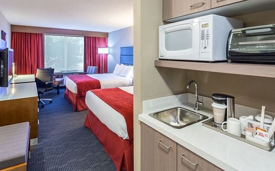 Cozy bed and TV arranged with mini kitchen area at Fort McMurray Hotels