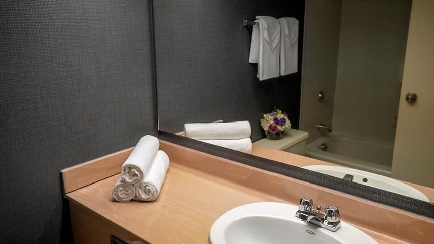 A bathroom with a sink & mirror at Cartier Place Suite Hotel
