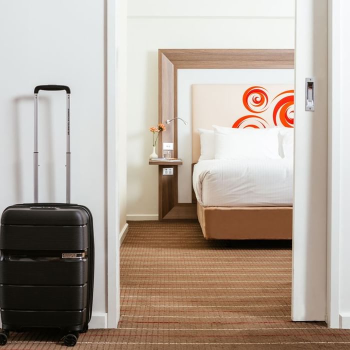 A travelling bag by a bedroom at Novotel Glen Waverley