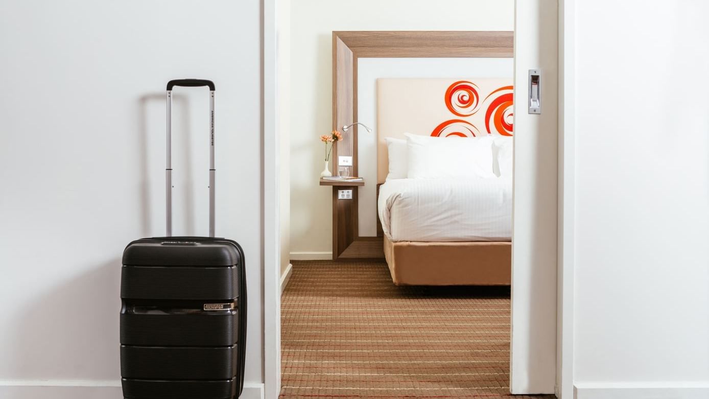 A travelling bag by a bedroom at Novotel Glen Waverley