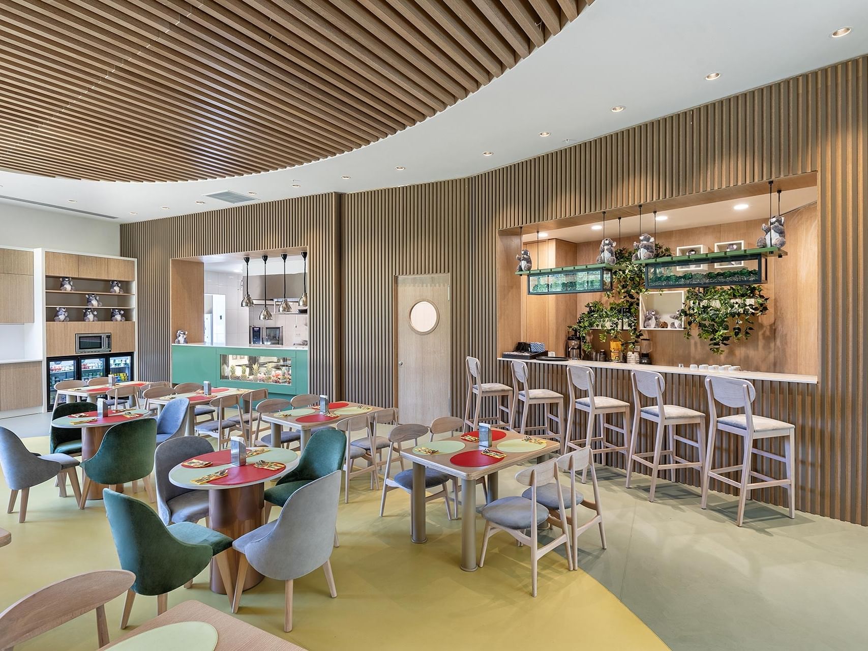 A modern restaurant at Titanic Luxury Collection Bodrum, offering a stylish ambiance with round tables, colorful chairs, and natural textures.