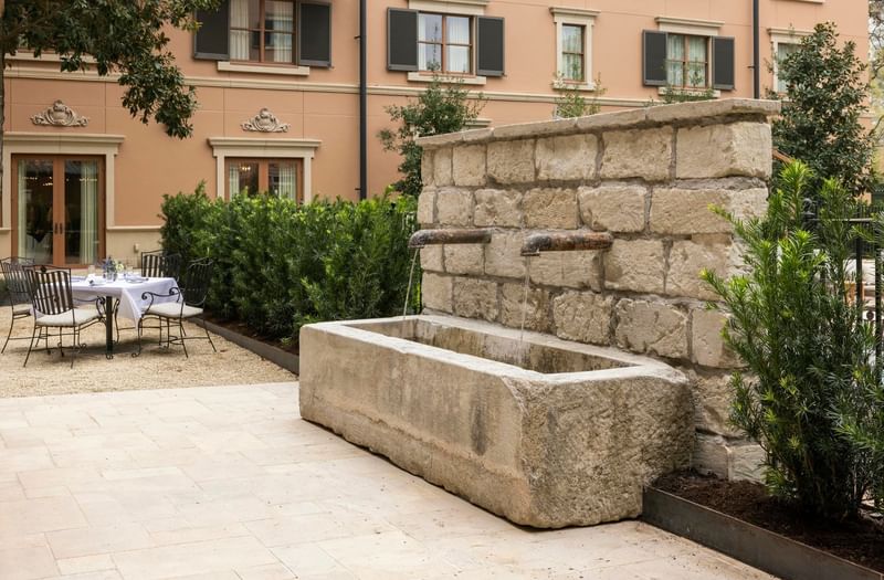 The Garden Courtyard dining area at Granduca Houston with a stone fountain surrounded by lush greenery