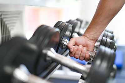 Hands of a man taking dumbbells from a rack at Nesuto Canberra