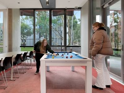 Two women playing pool in a recreational area at La Trobe University - North and South Apartments.