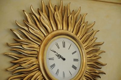 A clock with Roman numerals & sunburst style round metal frame at Grand Visconti Palace