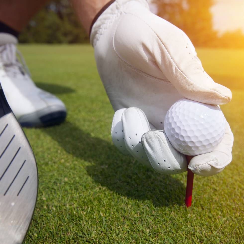 Hand placing a tee with golf ball at Falkensteiner Hotels