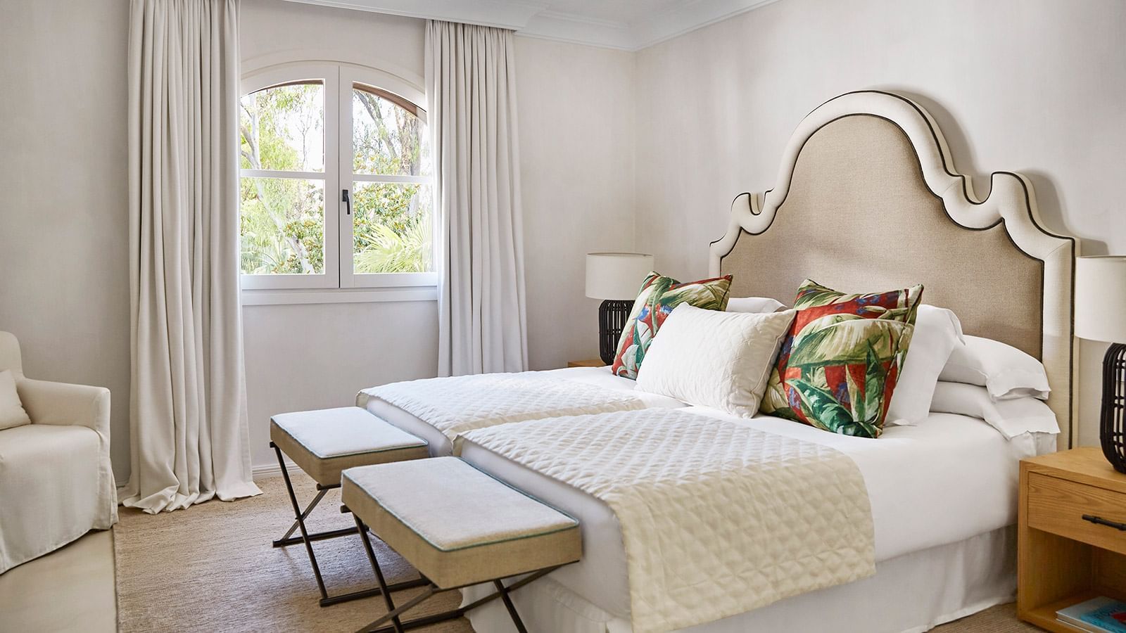 Four-Bedroom Villa kitchen with twin beds and footstools by an arched window at Marbella Club