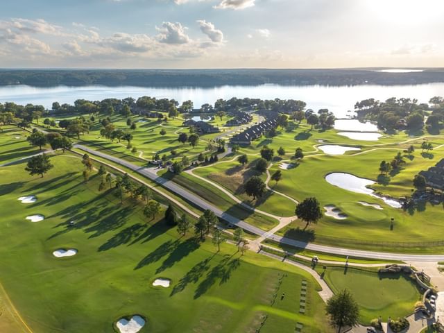 High angle aerial view of sprawling golf course fairways, sand traps, and lake at Shangri-La Resort and Golf Club