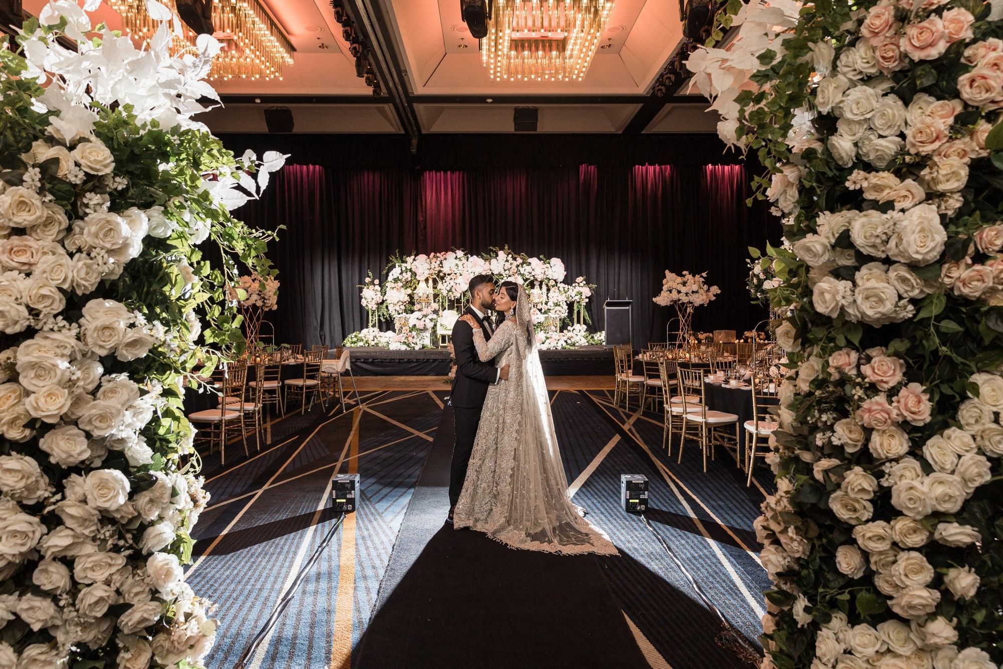 Couple embracing in a wedding hall decorated with floral arches at Sofitel Brisbane Central