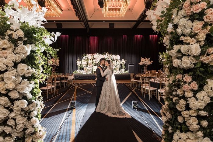Couple embracing in a wedding hall decorated with floral arches at Sofitel Brisbane Central