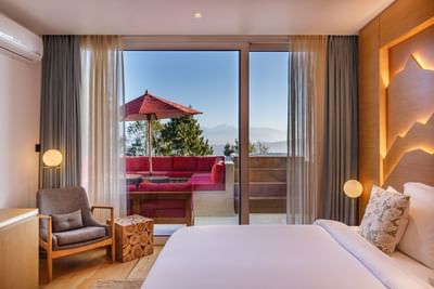 Comfy bed and balcony with a red sofa in Terraces Presidential Suites at The Terraces Resort & Spa