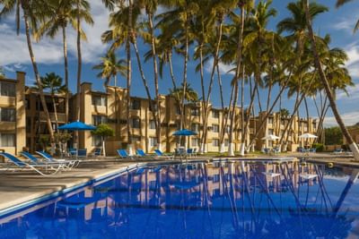 Pool with sunbeds & hotel exterior at Araiza Hotel Palmira