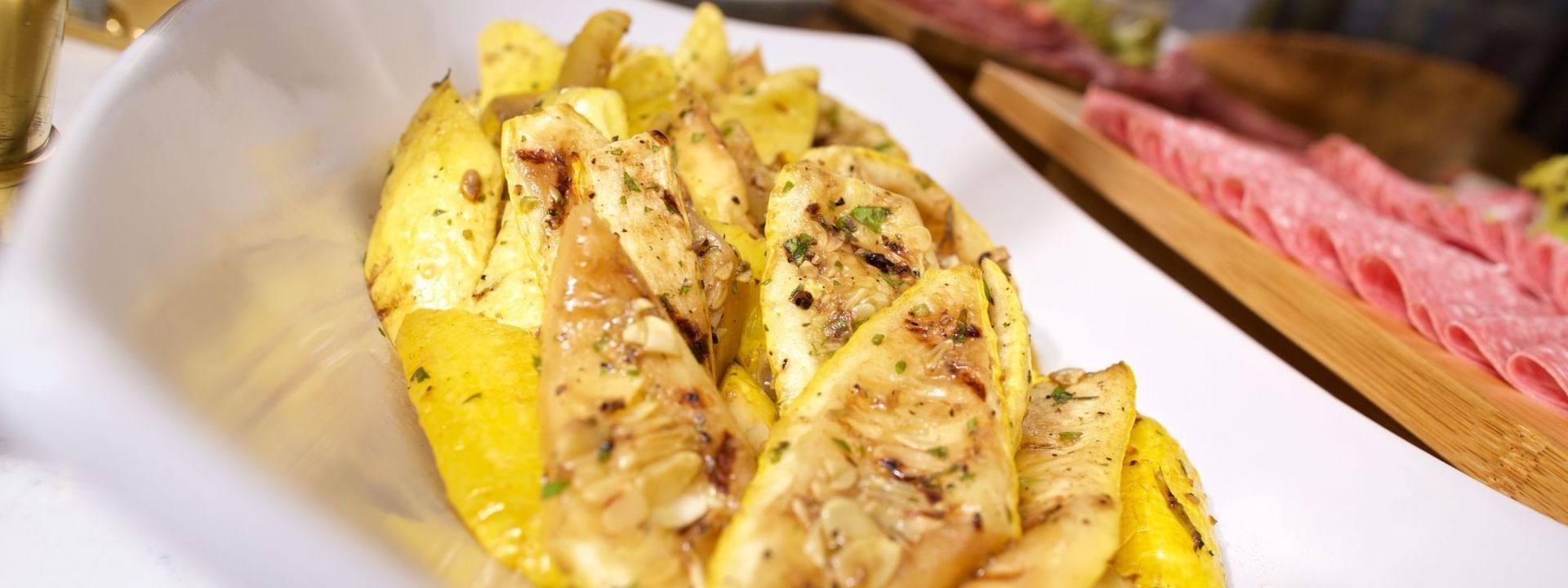 Grilled yellow squash in a white bowl by a buffet spread in Abbiocco at Warwick Paradise Island Bahamas