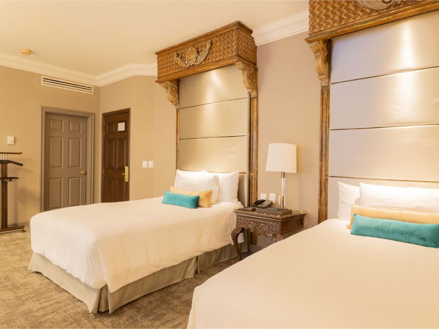 2 Double Master Suite with ornate wood carvings featuring teal accent pillows and lamps at Quinta Real Monterrey