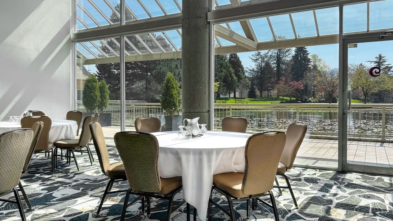 Indoor conference room with round tables, chairs, and a view of a pond.