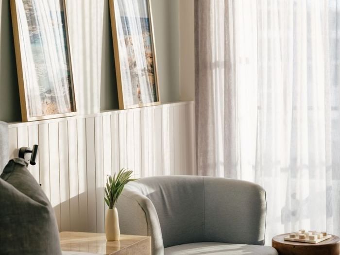 Sunset View King – Elysium Floor at Elysium Manly, showcasing two coastal artworks on a white wall above a grey armchair