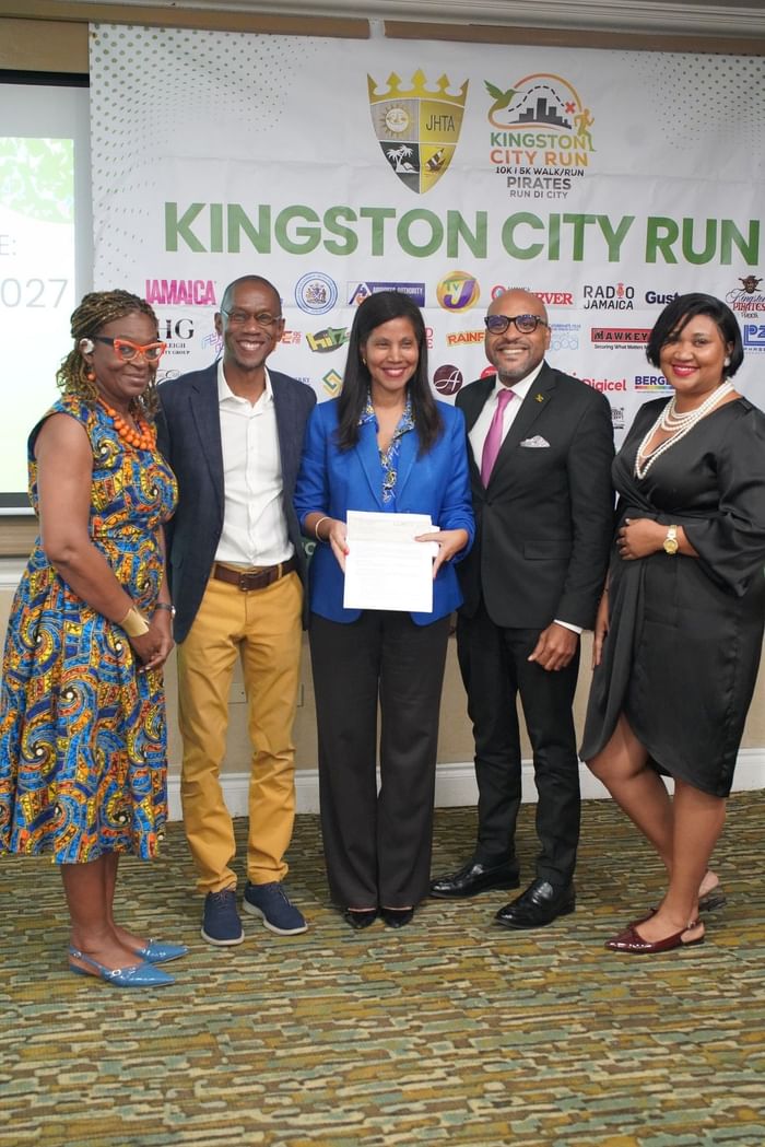 Five people posing with a signed document before the Kingston City Run banner at Courtleigh Hotel & Suites