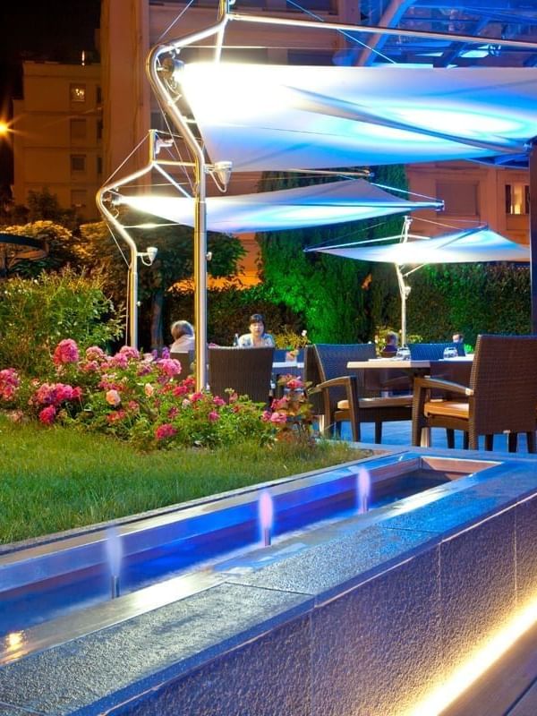 The Lounge Bar & Terrace with wicker chairs, modern awnings, & blue lighting at Warwick Reine Astrid - Lyon