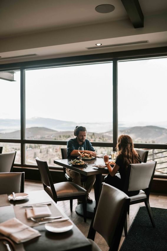 A couple dining in The 7880 Club with a distance view at Stein Eriksen Residences