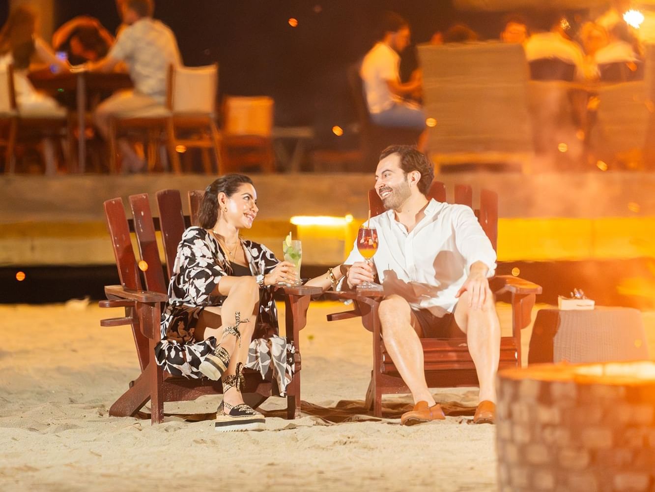 Couple sitting on beach chairs at night, with drinks in Indura Beach & Golf Resort