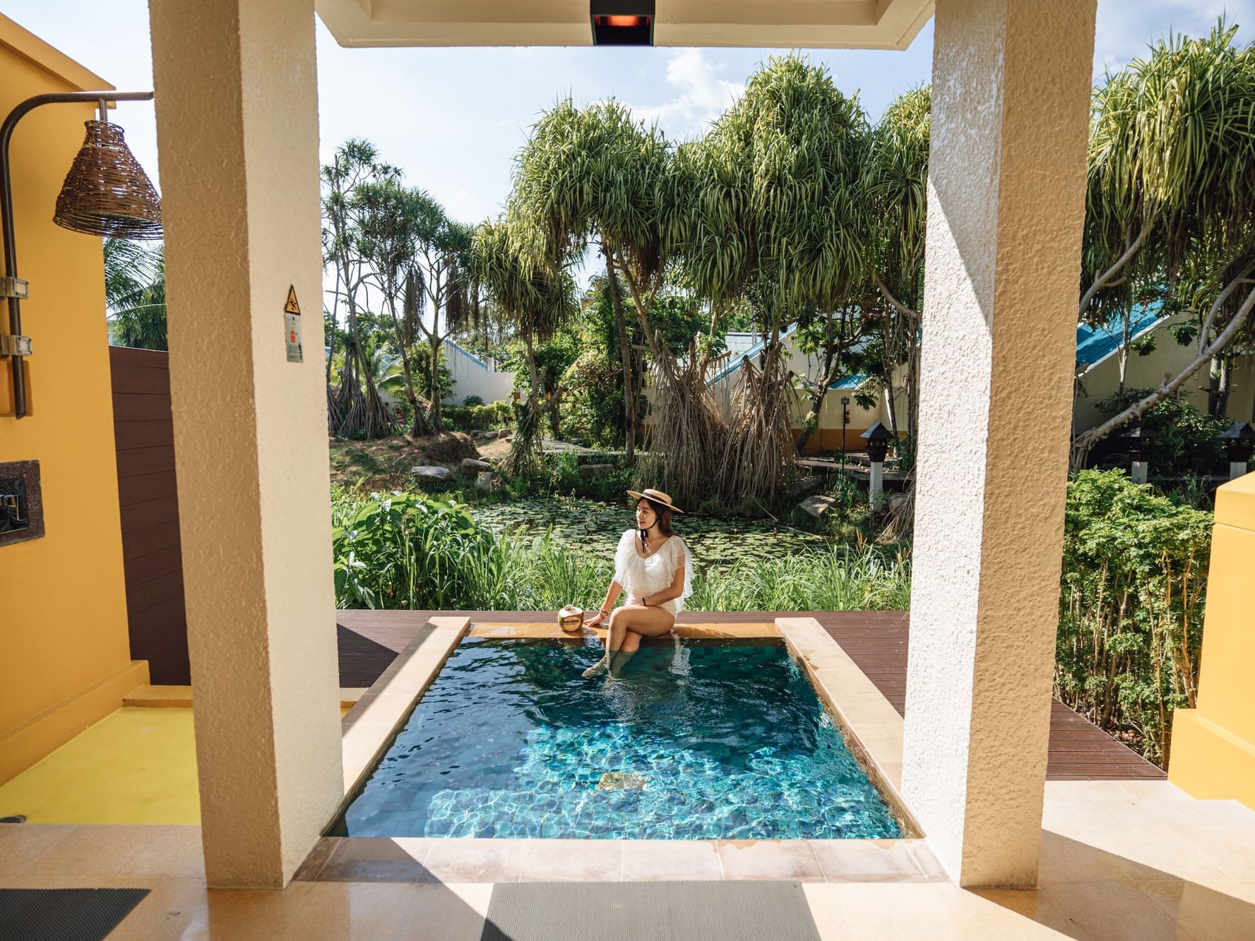 A woman is chilling in the plunge pool in Premium Garden Villa at Paradox Resort Phuket, surrounded by tropical garden and a view of lagoon