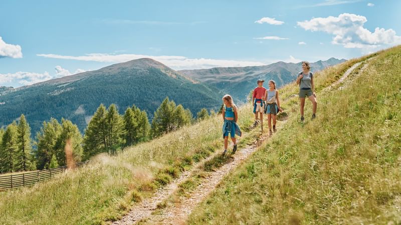 Familie wandert auf Pfad mit Bergpanorama im Hintergrund bei Falkensteiner Group