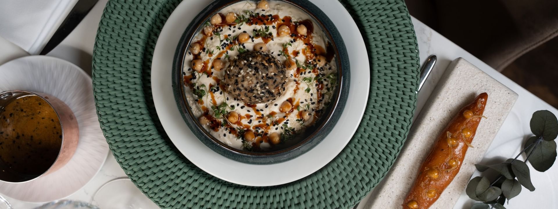 Bowl of creamy hummus topped with sesame seeds, & roasted carrot served in Le Céladon at Hotel Westminster Paris