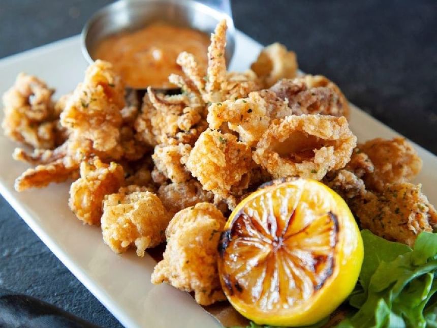 A dish of fried seafood with a lemon wedge served in a restaurant at Acclaim Hotel Calgary