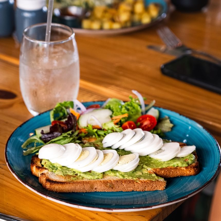 Healthy avocado toast with sliced hard-boiled eggs and a side salad served at El Nogal Restaurant, Riviera Hotel South Beach