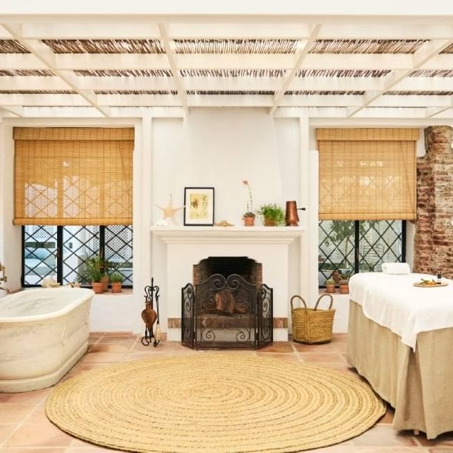 Elegant room with a fireplace, bathtub, and massage table at Marbella Club in Marbella.