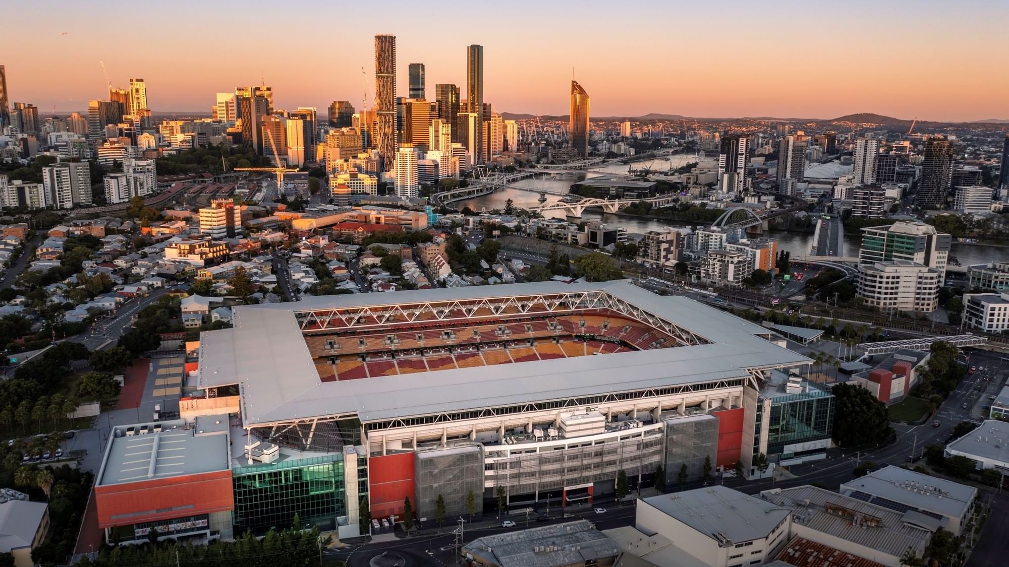 Aerial view of Suncorp Stadium and skyscrapers illuminated by sunset near Sofitel Brisbane Central