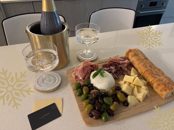 A silver champagne bucket, two sparkling water glasses, and a charcuterie board with olives and prosciutto at ReStays Ottawa