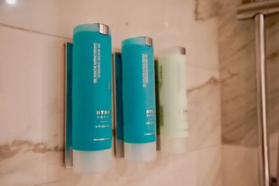 Wall-mounted teal and green Hydro Basic refreshing shower gel dispensers in the bathroom at The Abidah Hotel by Accra