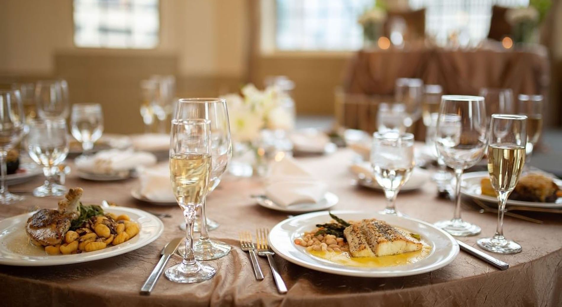 Plates of gourmet food and wine glasses set on a table at Warwick Allerton Chicago