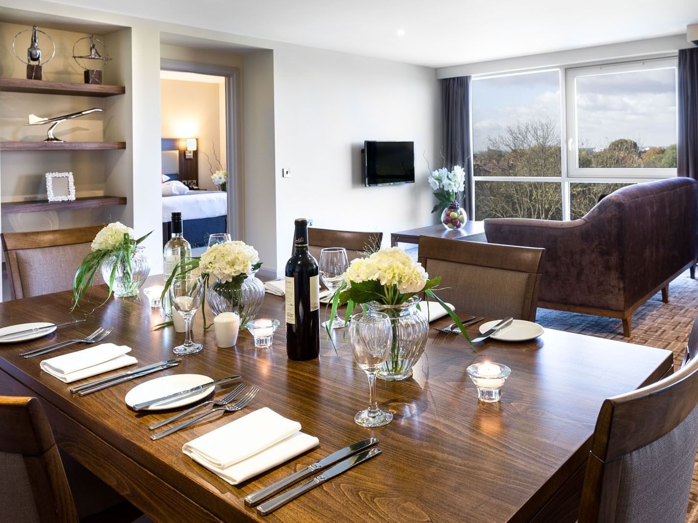Dining table with glassware and floral arrangements by the TV lounge in the One Bedroom Suite at Heston Hyde Hotel 