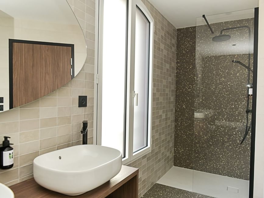 Salle de bain élégante avec douche vitrée et lavabo ovale à l'Hôtel Rivella.